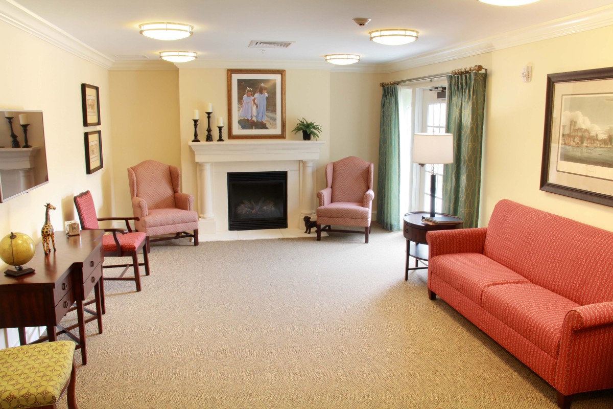 A cozy living room with a fireplace, armchairs, and a sofa.
