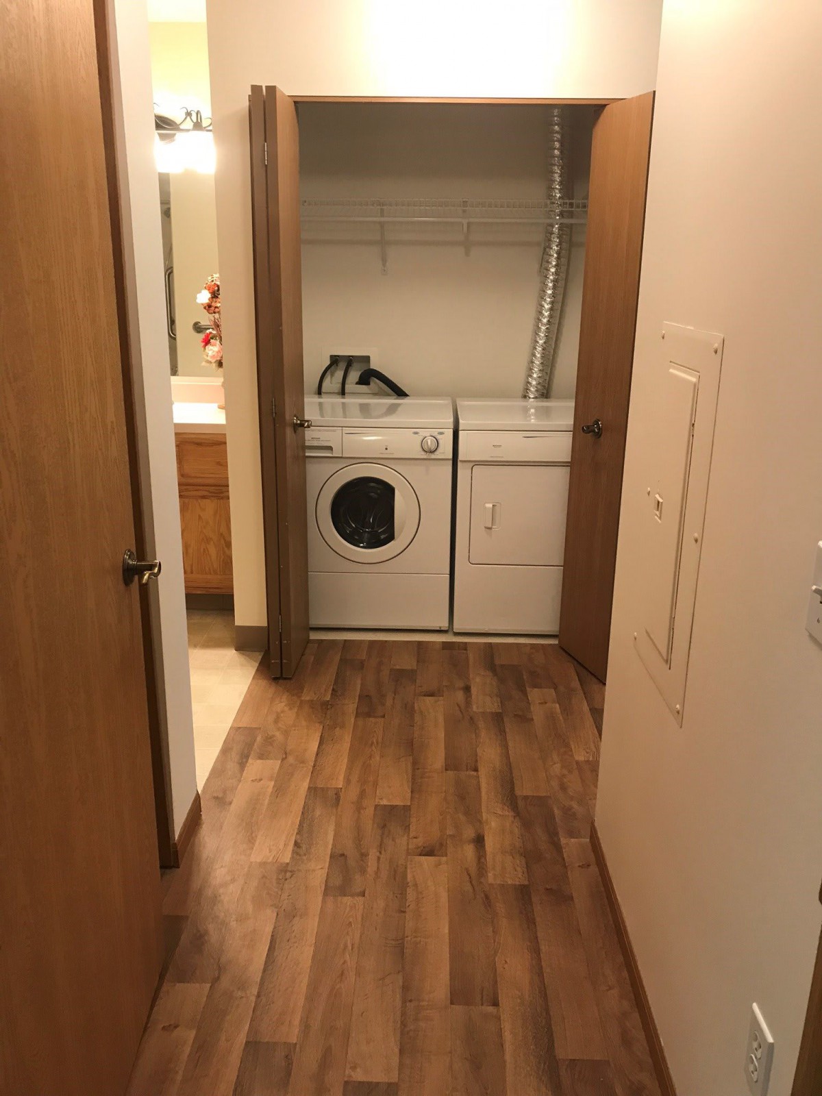 A compact laundry area with a washer and dryer set, featuring wood flooring.