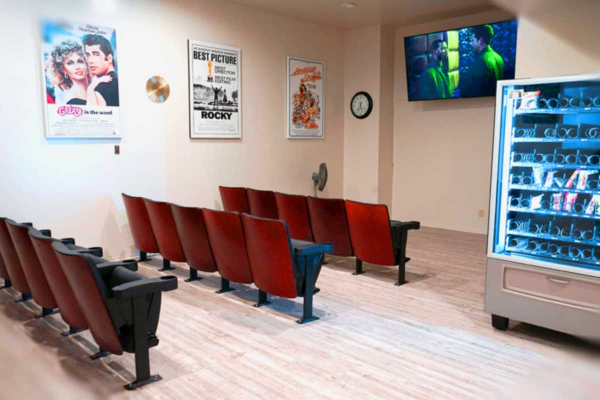 An empty waiting area with theater-style seating and a television on the wall, decorated with movie posters.
