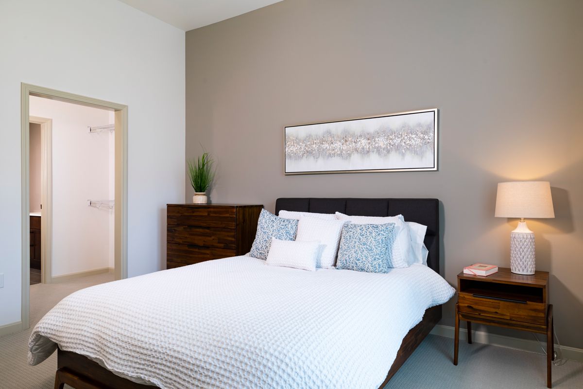 A modern and minimalist bedroom with a neatly made bed, neutral colors, and simple decor.