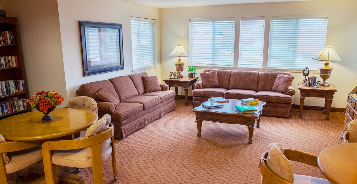 A cozy living room with two sofas, a coffee table, and a lamp by the window.