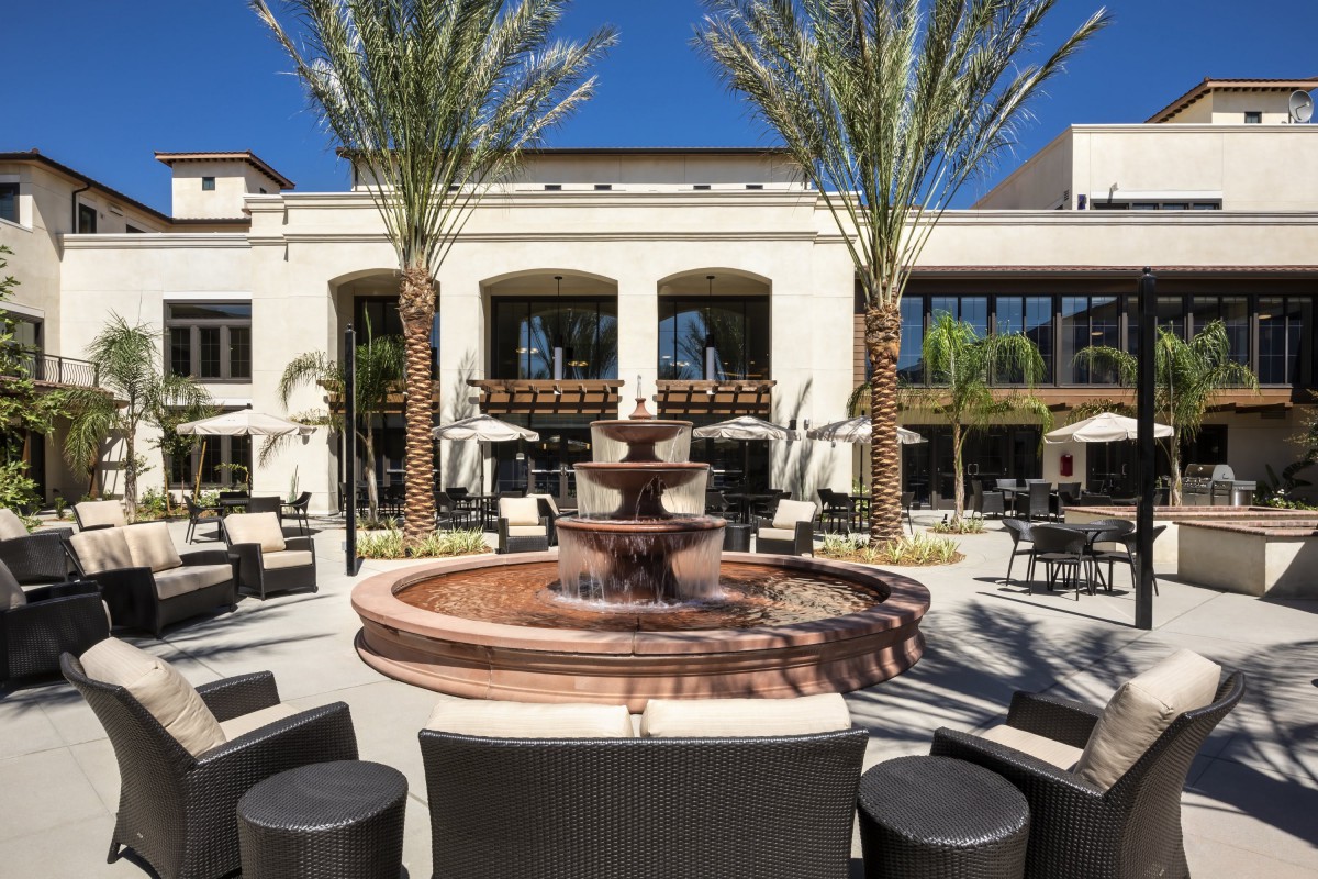 A beautiful outdoor seating area with a central fountain surrounded by palm trees and modern architecture.