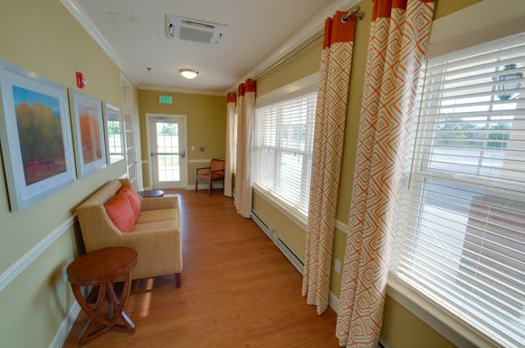 A cozy hallway with a couch, large windows, and decorative curtains.