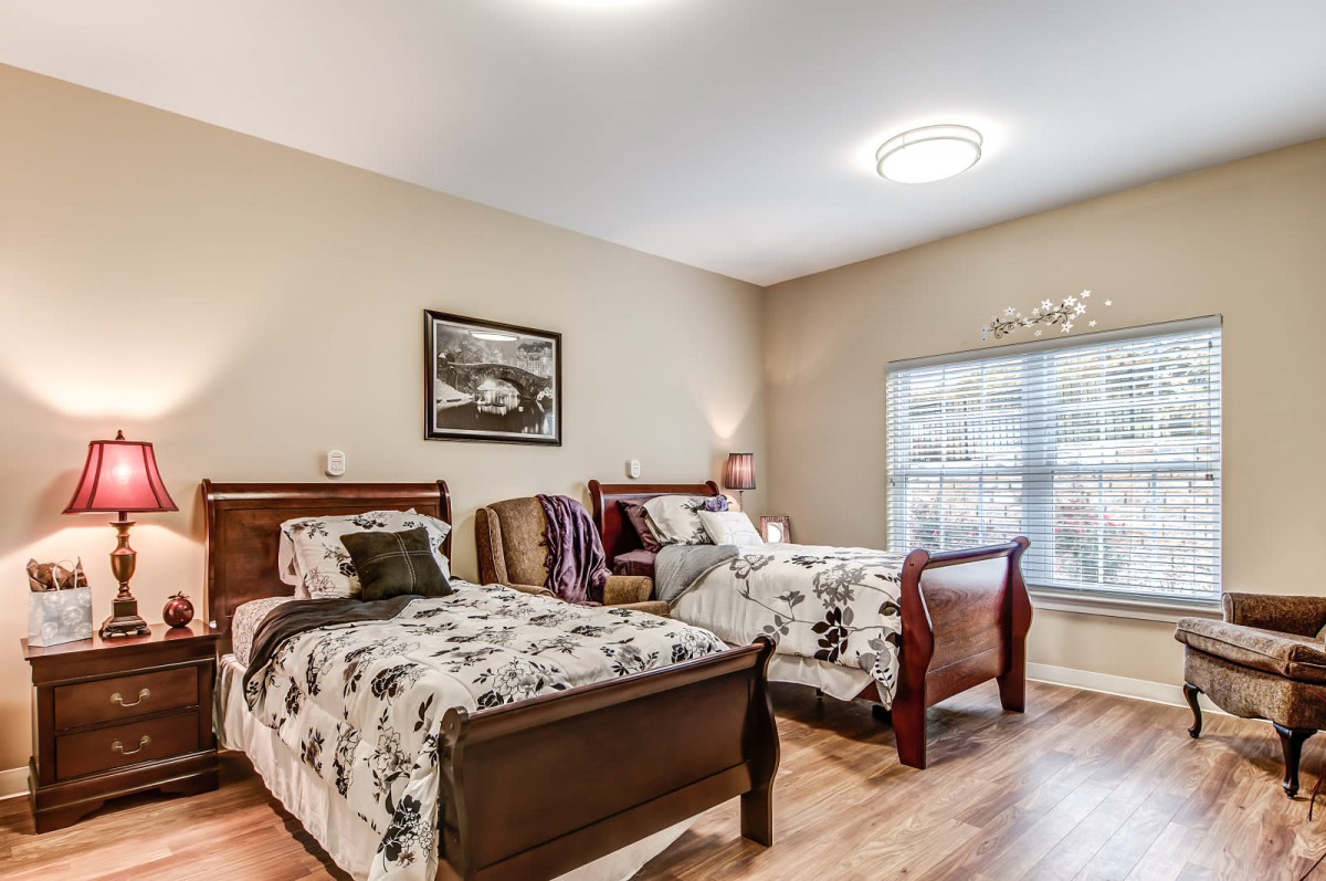 A cozy bedroom featuring two twin beds with patterned bedspreads, decorative pillows, and warm lighting.