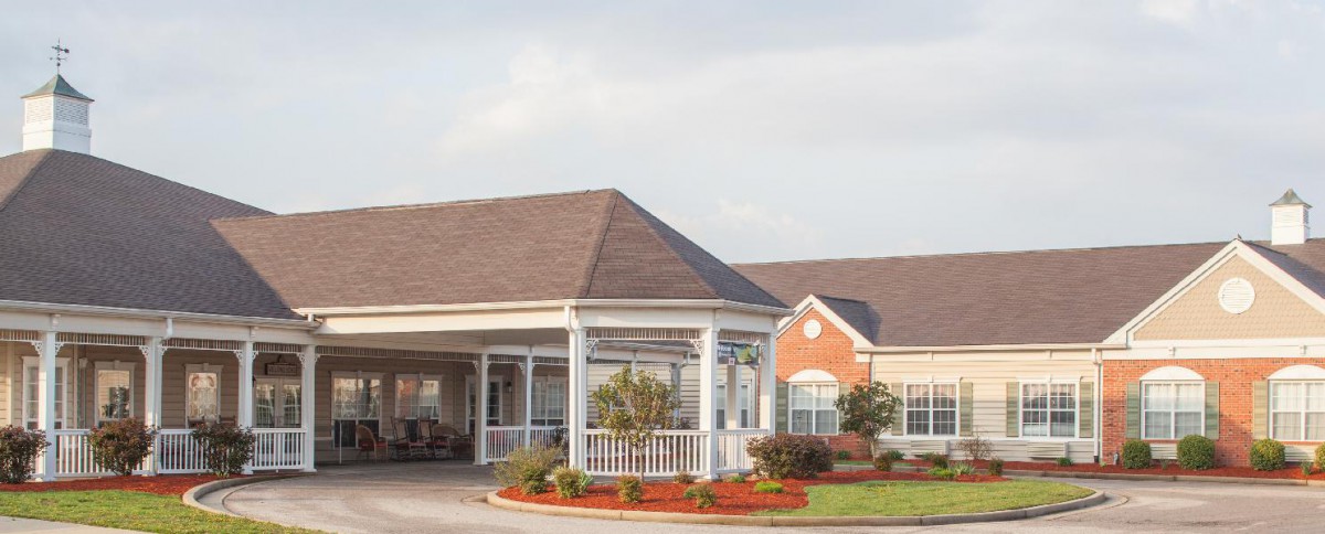 A building with a covered entrance and well-maintained landscaping on a clear day.