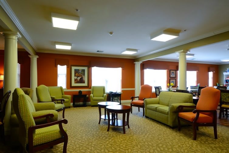 A spacious and well-lit living room with comfortable sofas, chairs, and tables arranged neatly.