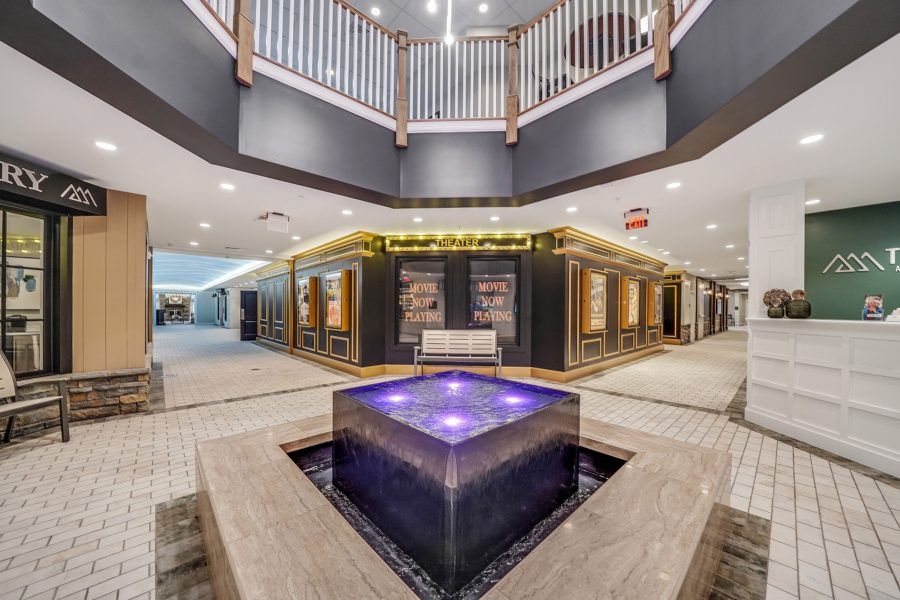 A modern shopping center interior featuring a central illuminated fountain.