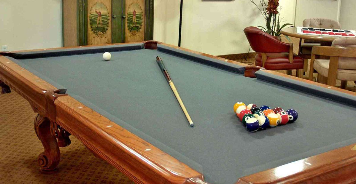 A pool table with a cue stick and racked billiard balls ready for play.