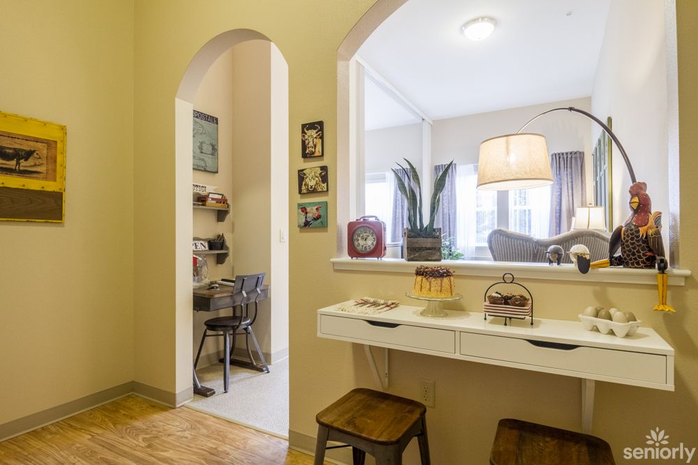 A cozy home interior featuring a small desk area leading into a living room with stylish decor.