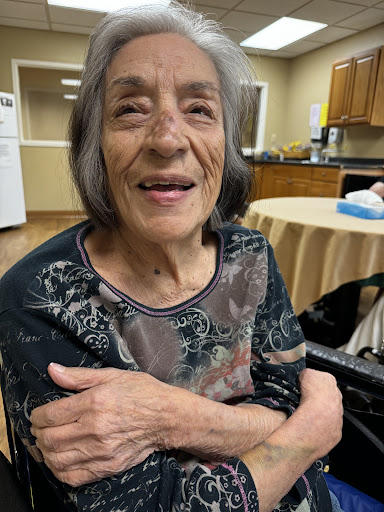 A joyful elderly woman smiling warmly in a community setting.