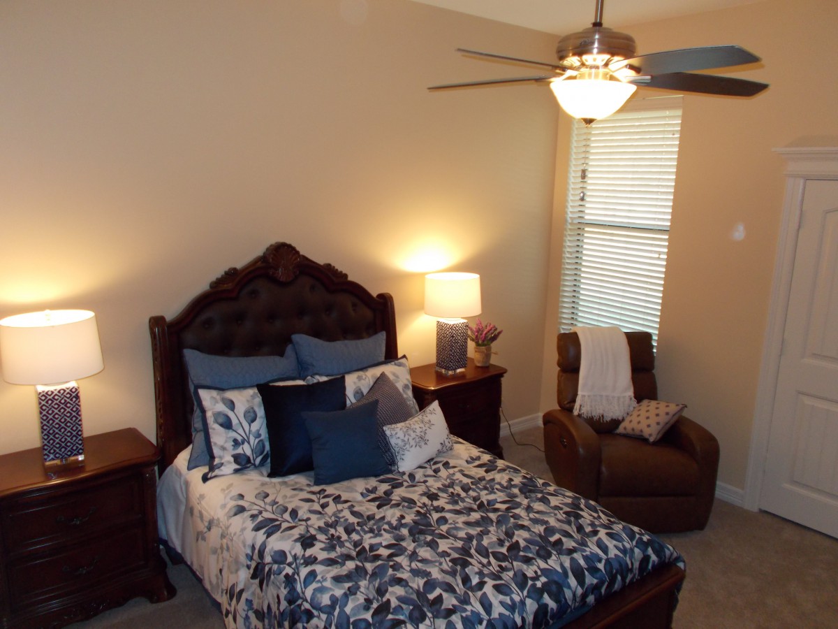A cozy bedroom with a well-decorated bed and an armchair in the corner.
