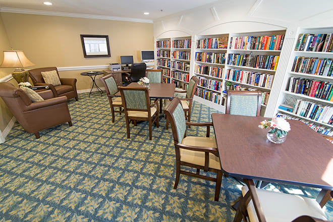 A cozy library room with bookshelves, tables, and computers for reading and study.
