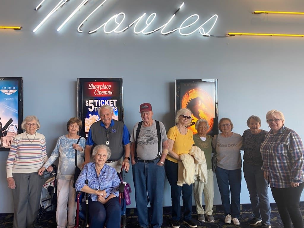 A group of people standing together in front of movie posters at a theater.