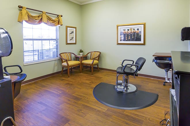 A spacious and well-lit hair salon with seating and a styling station.