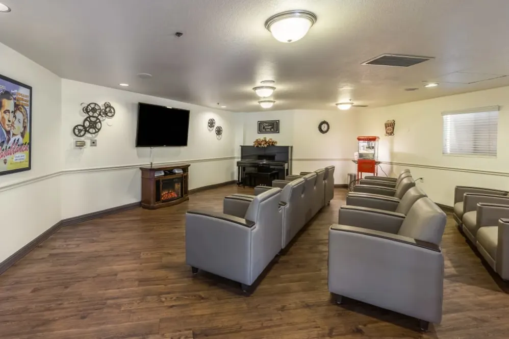 A modern home theater room with multiple chairs, a large television, and wooden flooring.