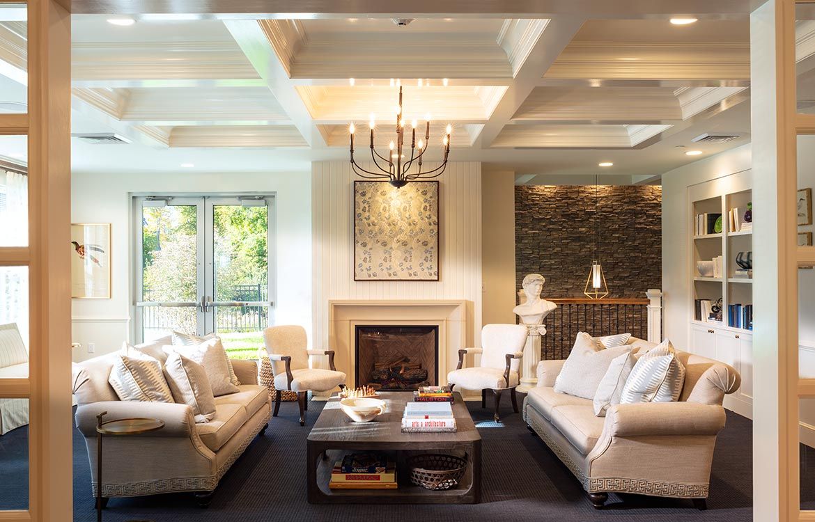 A luxurious living room featuring elegant furniture, a central fireplace, and a chandelier.