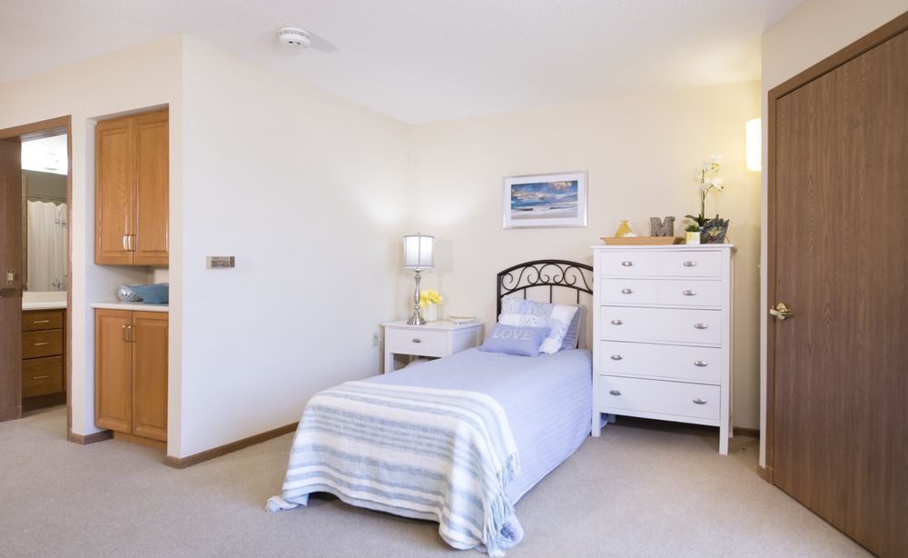 A cozy bedroom with a single bed, white furniture, and minimalist decor.