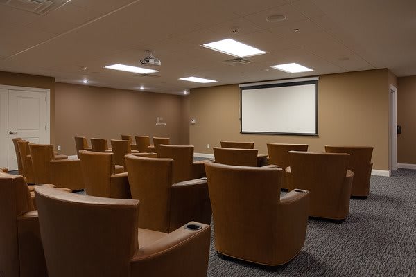 A small auditorium with comfortable seating and a projector screen at the front.
