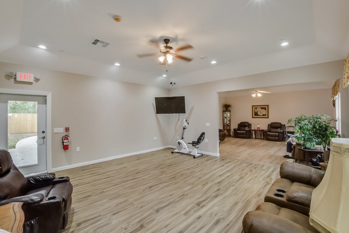 A spacious exercise room with gym equipment and wooden flooring.