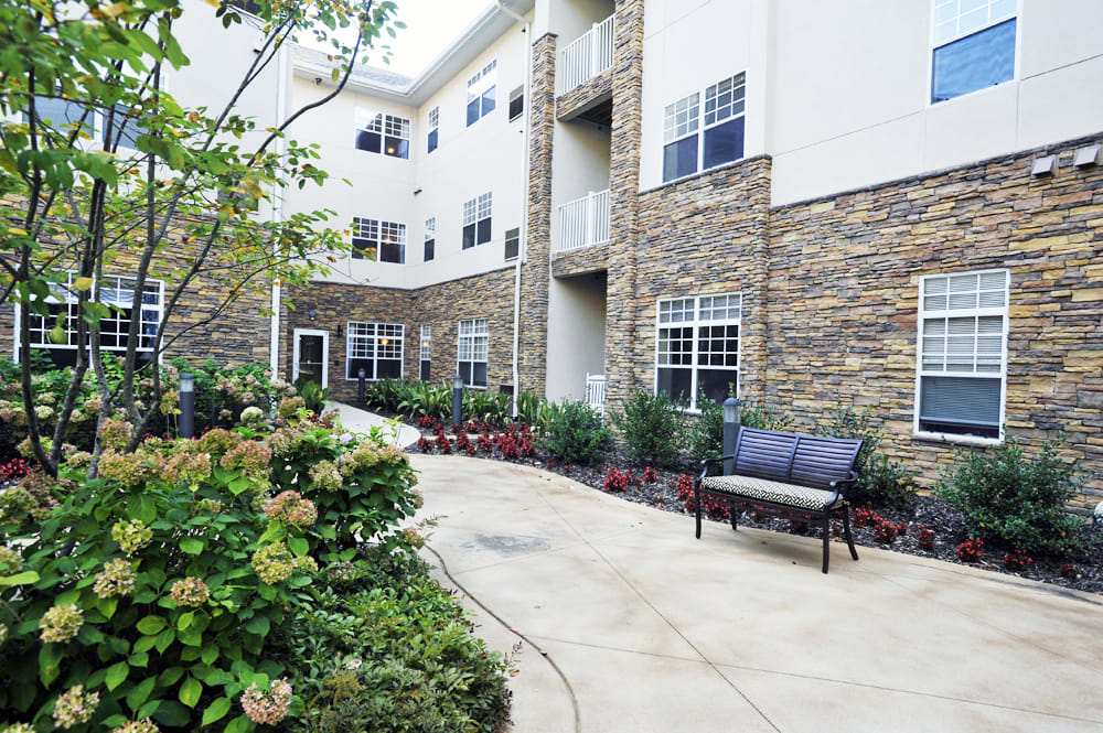 A view of an apartment building's courtyard with benches and landscaping.