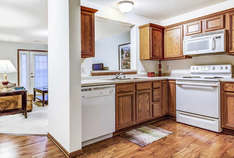 A cozy kitchen with wooden cabinets, a dishwasher, and an oven on a hardwood floor.