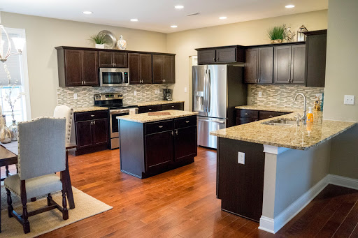 A modern kitchen featuring dark oak cabinets, granite countertops, and stainless steel appliances in an open layout.