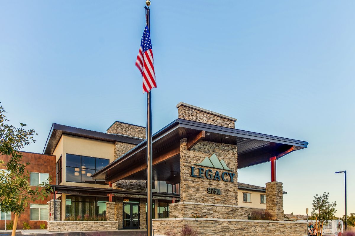 A modern building with a stone facade and an American flag in front, labeled 'Legacy'.