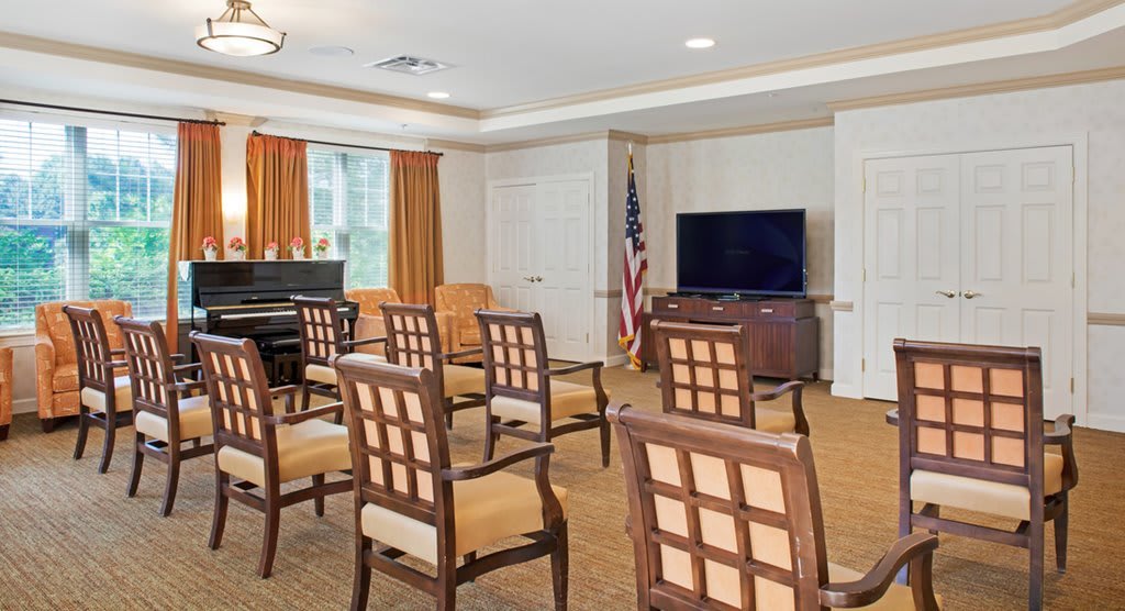 A small meeting room with arranged chairs, a television, and a piano.