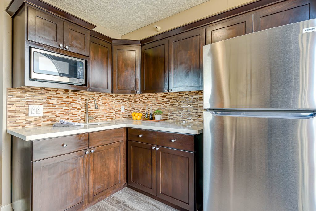 Modern kitchen with dark wood cabinetry and stainless steel appliances.