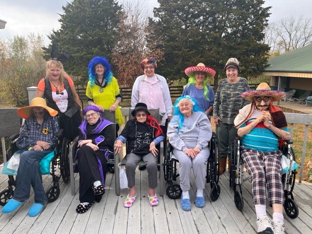 A group of elderly people dressed in colorful costumes and hats, enjoying time outdoors.