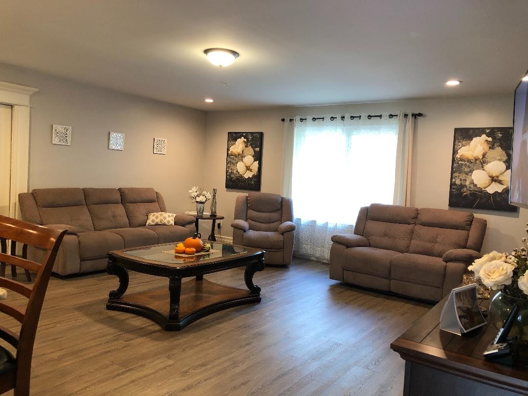 A cozy living room featuring comfortable sofas and a stylish coffee table, complemented by wall art and natural light from the window.