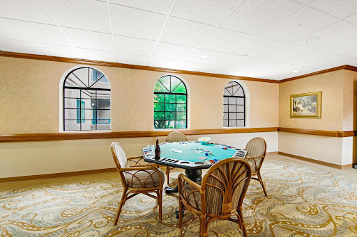 A tranquil room featuring a round table with wicker chairs and large windows, inviting natural light.