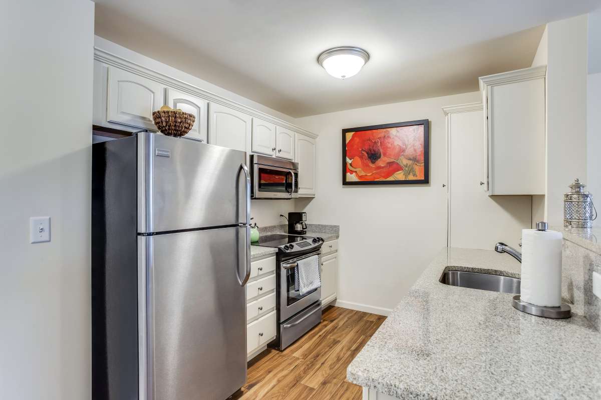A modern kitchen with stainless steel appliances and wood flooring.