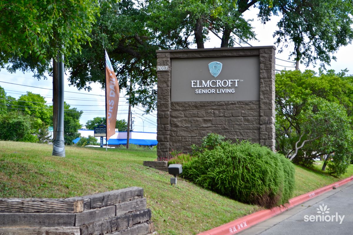 A stone sign with landscaping and trees in the background.