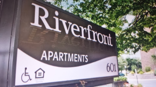 Sign for Riverfront Apartments featuring the address.
