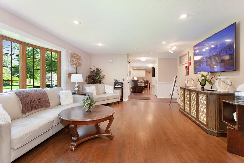 A spacious living room with modern decor, featuring a comfortable sofa, coffee table, and wooden flooring.