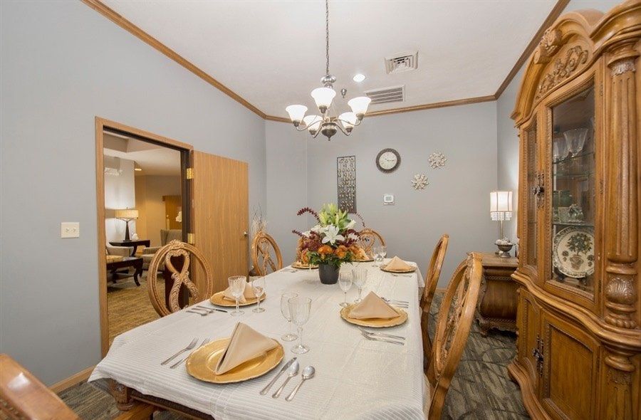 A neatly set dining room with a chandelier and decorative elements.