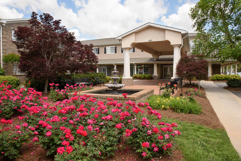 A beautiful garden with vibrant flowers and a fountain in front of a large building.