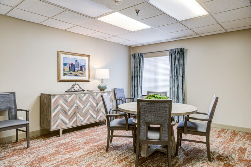 A well-lit dining room with a round table, several chairs, and tasteful decor.