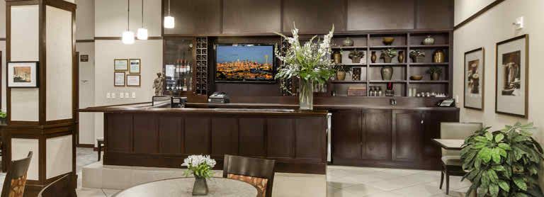 A modern lobby with a sleek reception desk, a large floral arrangement, and a television mounted on the wall.