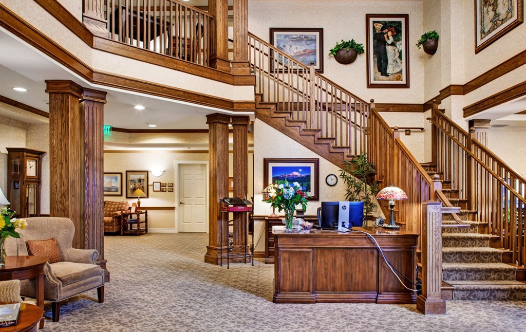 A welcoming lobby area featuring a wooden staircase, reception desk, and elegant decor.