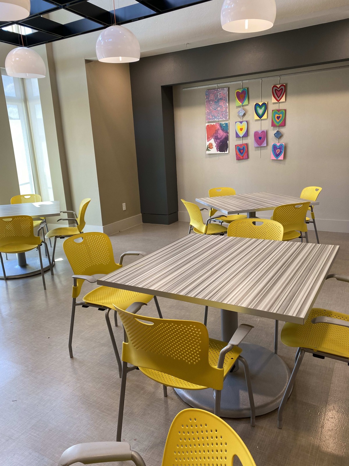 A modern cafeteria with yellow chairs and decorative wall art.