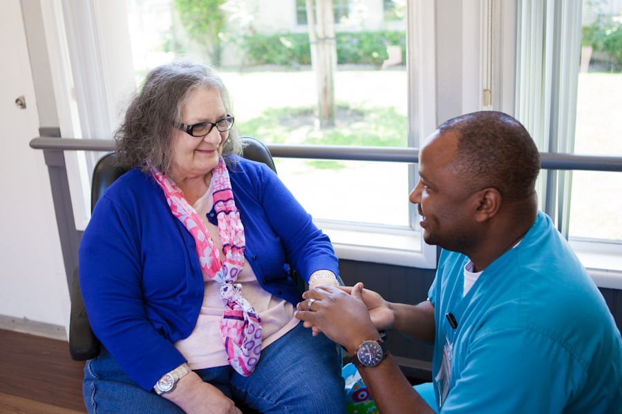 A caregiver interacting with a senior woman, providing support and care.