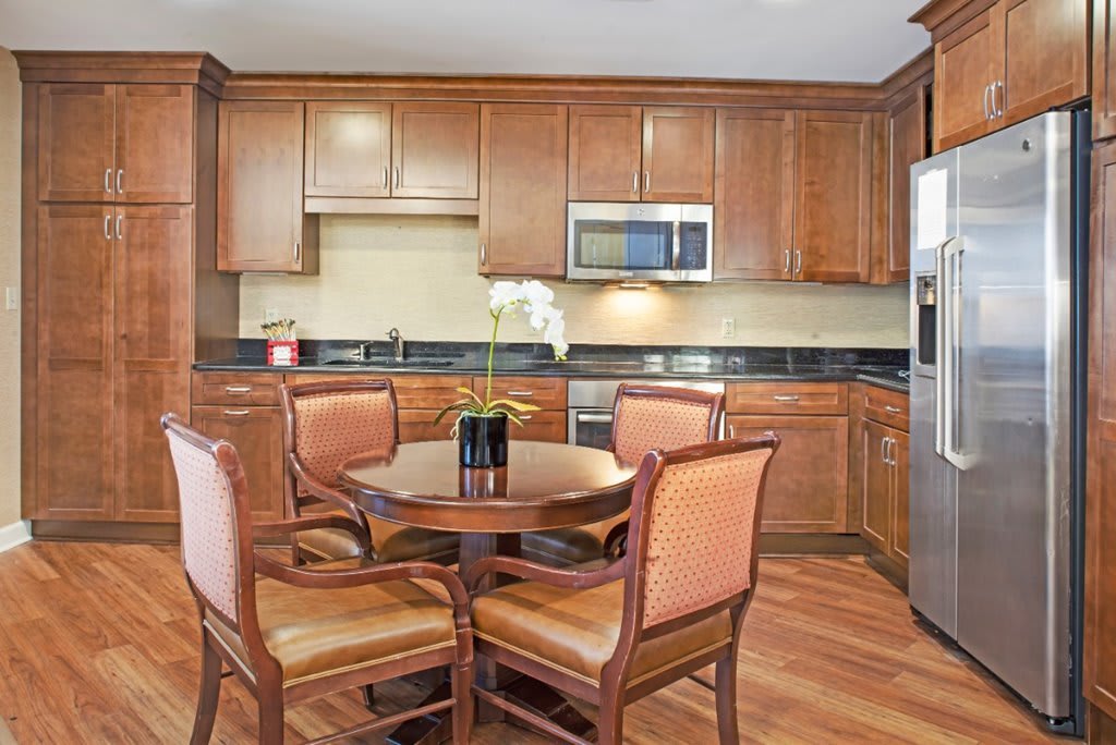 A kitchen with wooden cabinets and a round dining table surrounded by chairs.