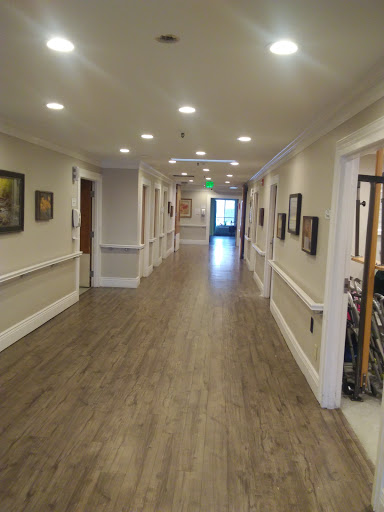 A well-lit hallway featuring wooden flooring and artworks on the walls.
