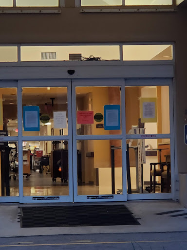 The entrance to a building showcasing glass doors and visible interior furniture.
