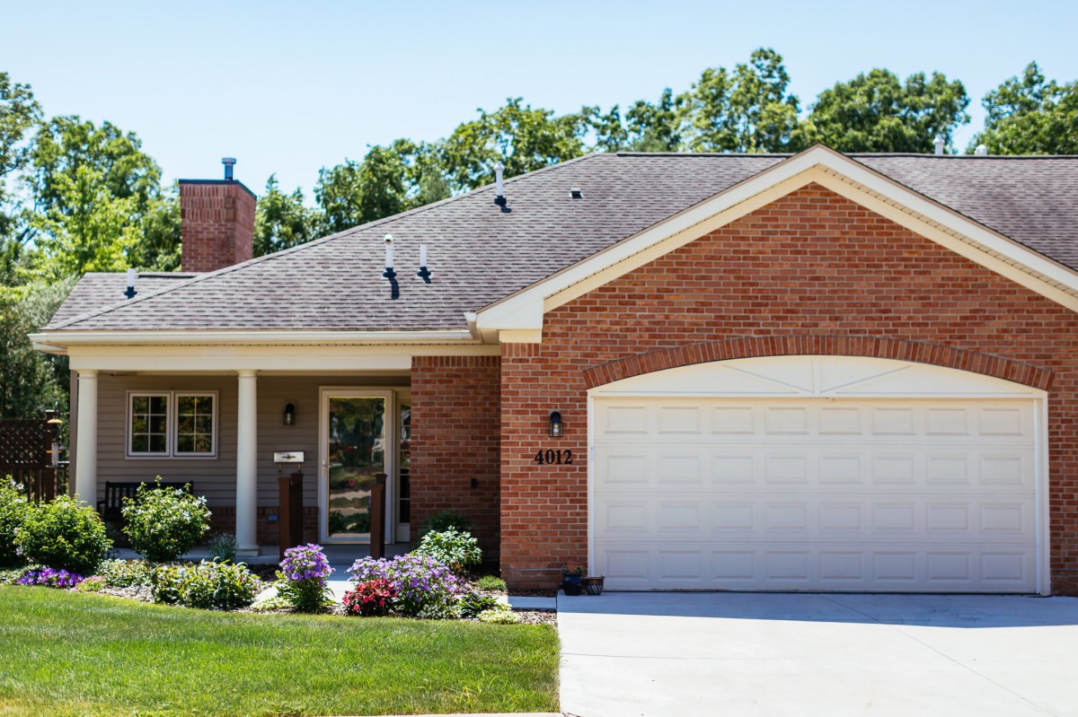 A suburban brick house with a two-car garage and a neatly maintained front yard.
