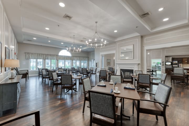 An elegant and spacious dining room with chandeliers, neatly arranged tables, and comfortable seating.