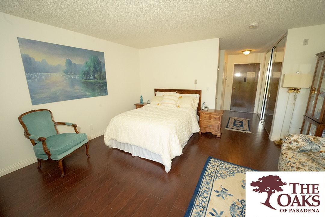 A cozy bedroom featuring a bed with white linens, wooden furniture, and a painting on the wall.