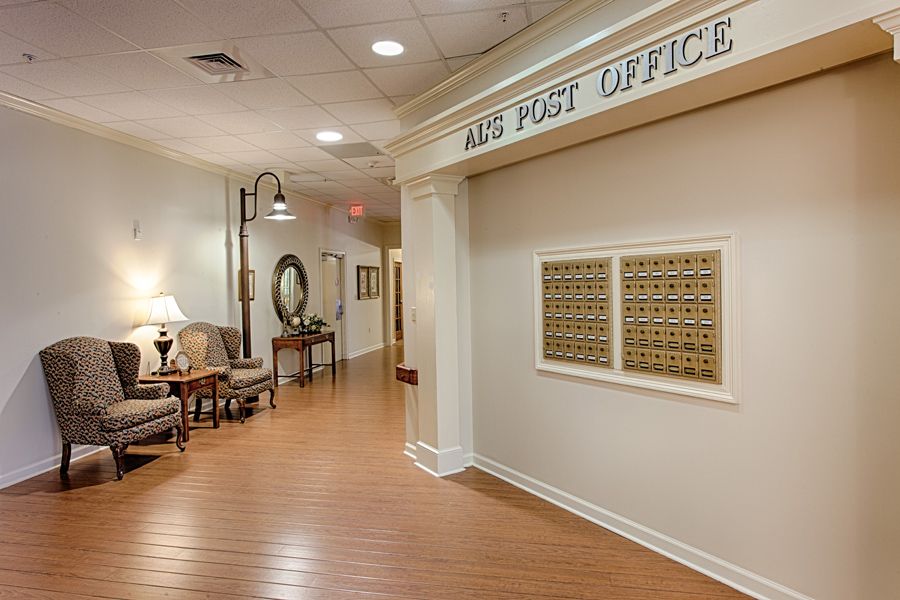 A hallway with a small post office area, featuring mailboxes and cozy seating.